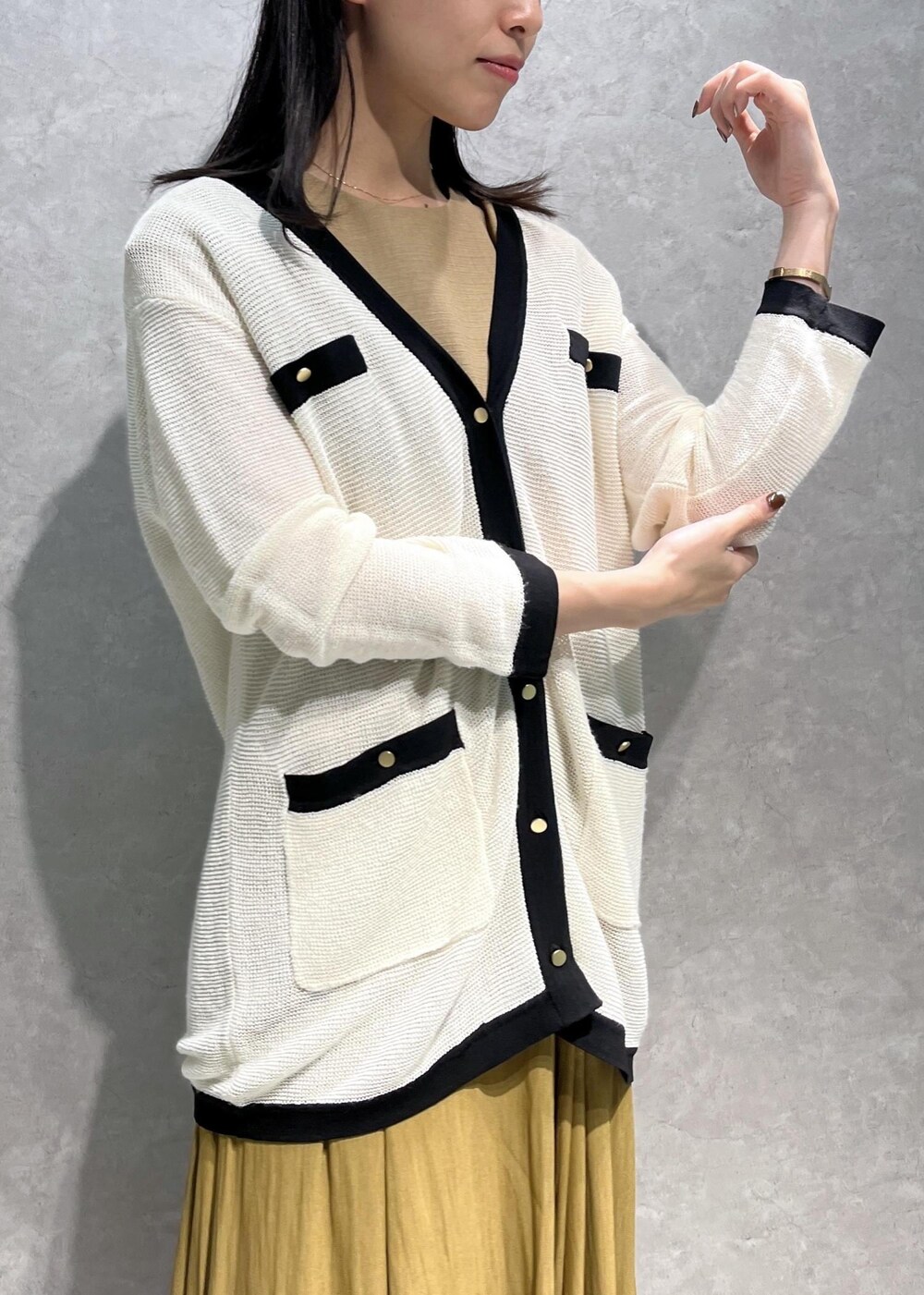 ブラック系のパンプス、ブラック系のハンドバッグ、ホワイト系のカーディガン/ボレロを着用したレディースの夏コーディネートの5枚目の写真