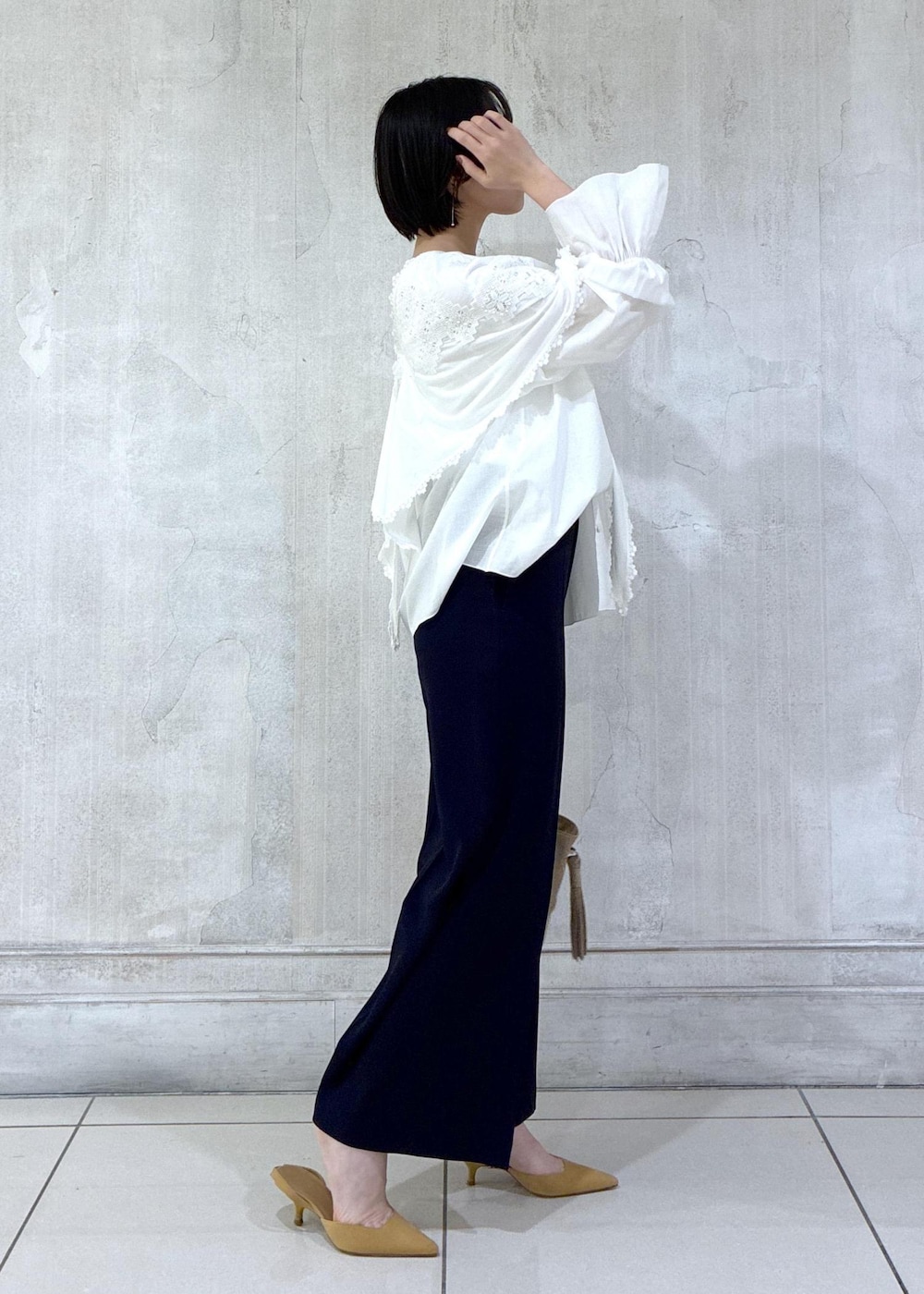 ベージュ系のショルダーバッグ、ホワイト系のシャツ/ブラウス、ブルー系のスラックスを着用したレディースの冬コーディネートの4枚目の写真