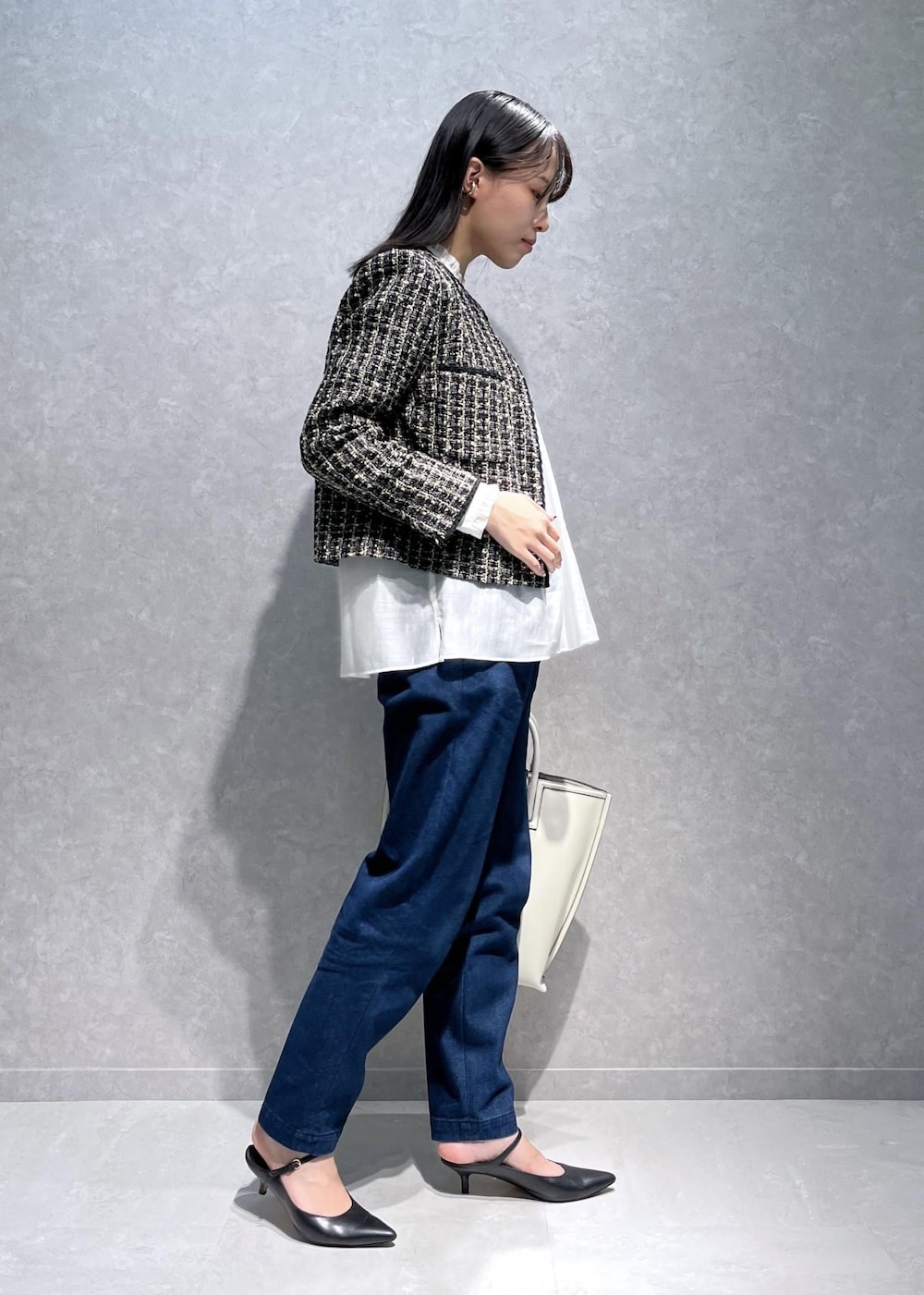 ブラック系のパンプス、ホワイト系のトートバッグ、ブルー系のデニムパンツを着用したレディースの秋コーディネートの2枚目の写真
