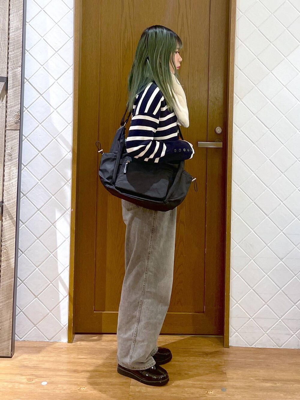 ブラック系のショルダーバッグ、グレー系のデニムパンツ、ブラック系のローファーを着用したレディースの冬コーディネートの2枚目の写真