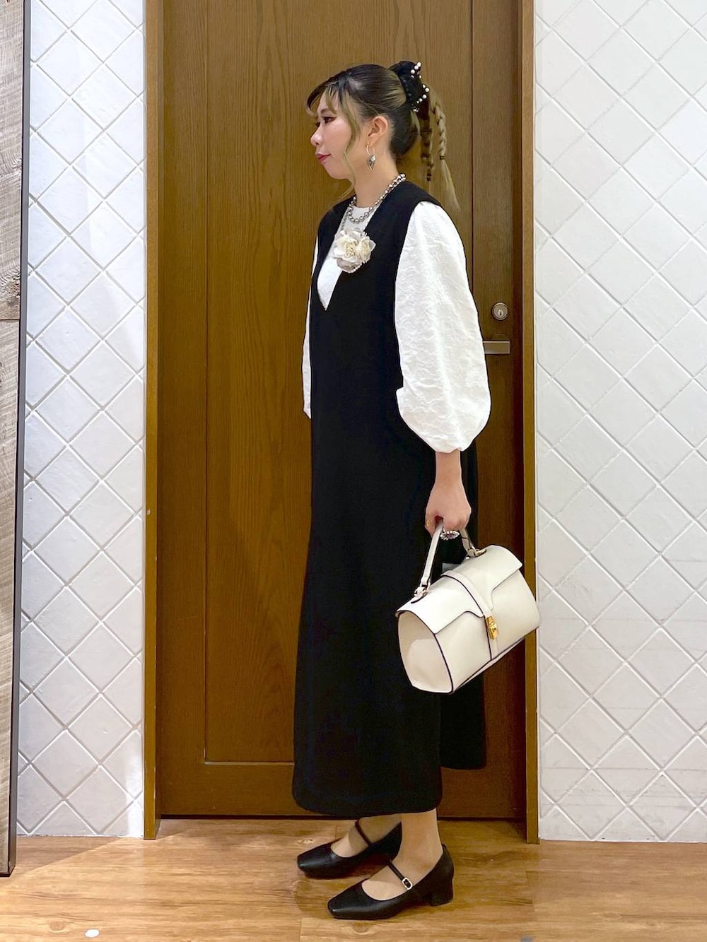 ホワイト系のシャツ/ブラウス、ブラック系のパンプス、ブラック系のジャンパースカートを着用したレディースの冬コーディネートの2枚目の写真