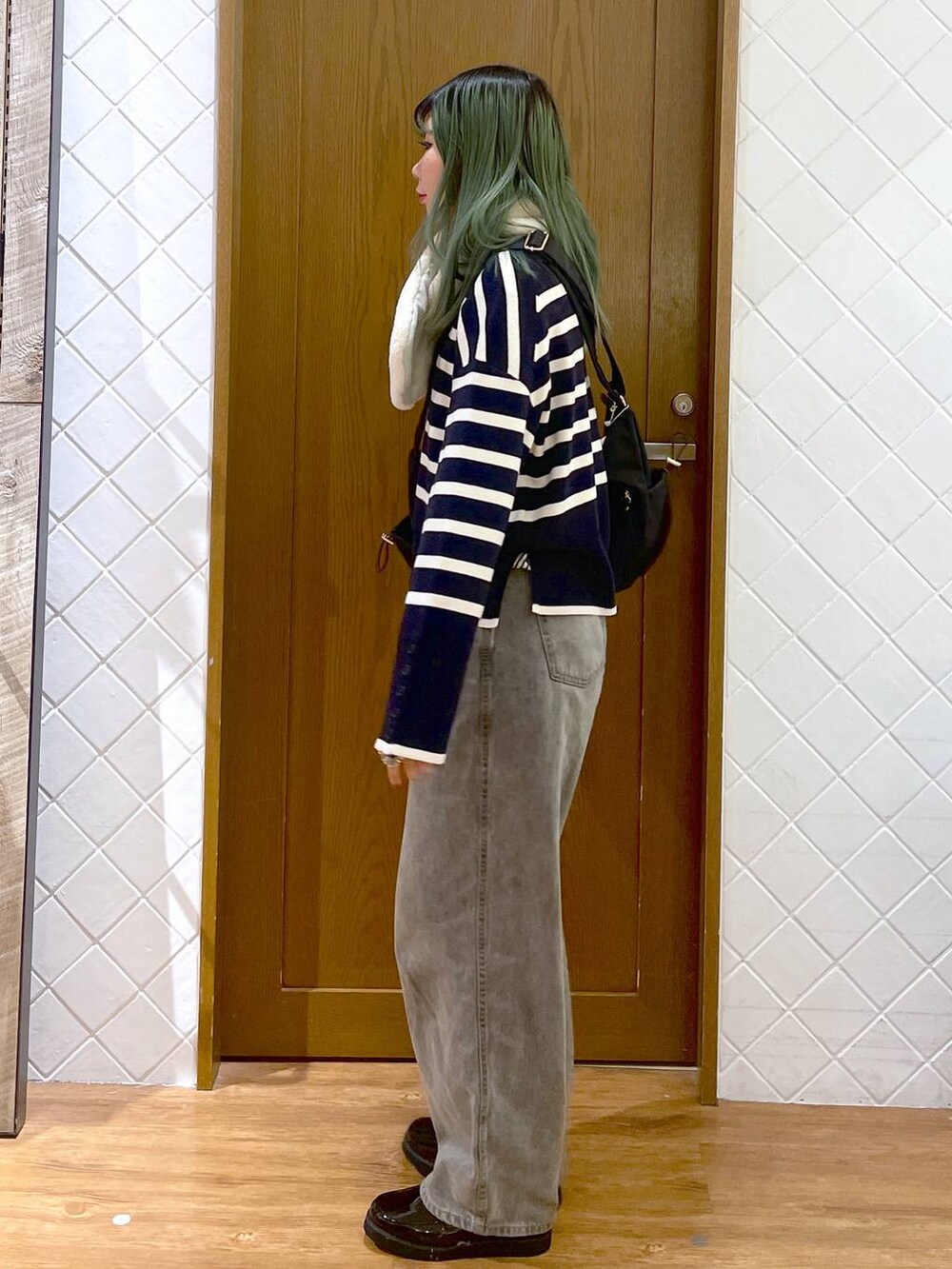 ブラック系のショルダーバッグ、グレー系のデニムパンツ、ブラック系のローファーを着用したレディースの冬コーディネートの3枚目の写真