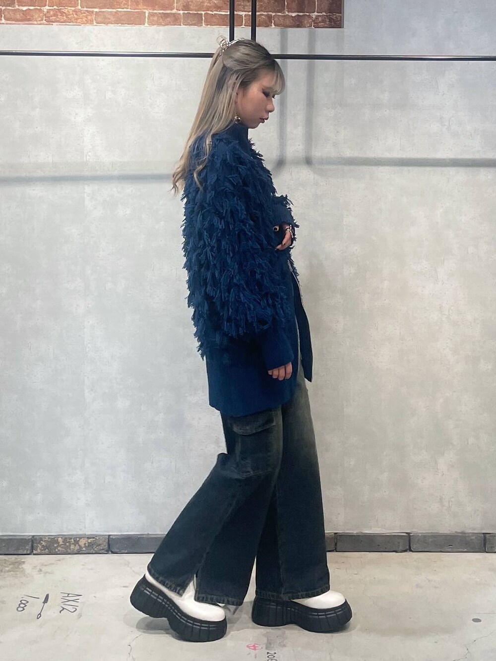 ホワイト系のブーツ、ブラック系のTシャツ/カットソー、ブルー系のニット/セーターを着用したレディースの冬コーディネートの2枚目の写真