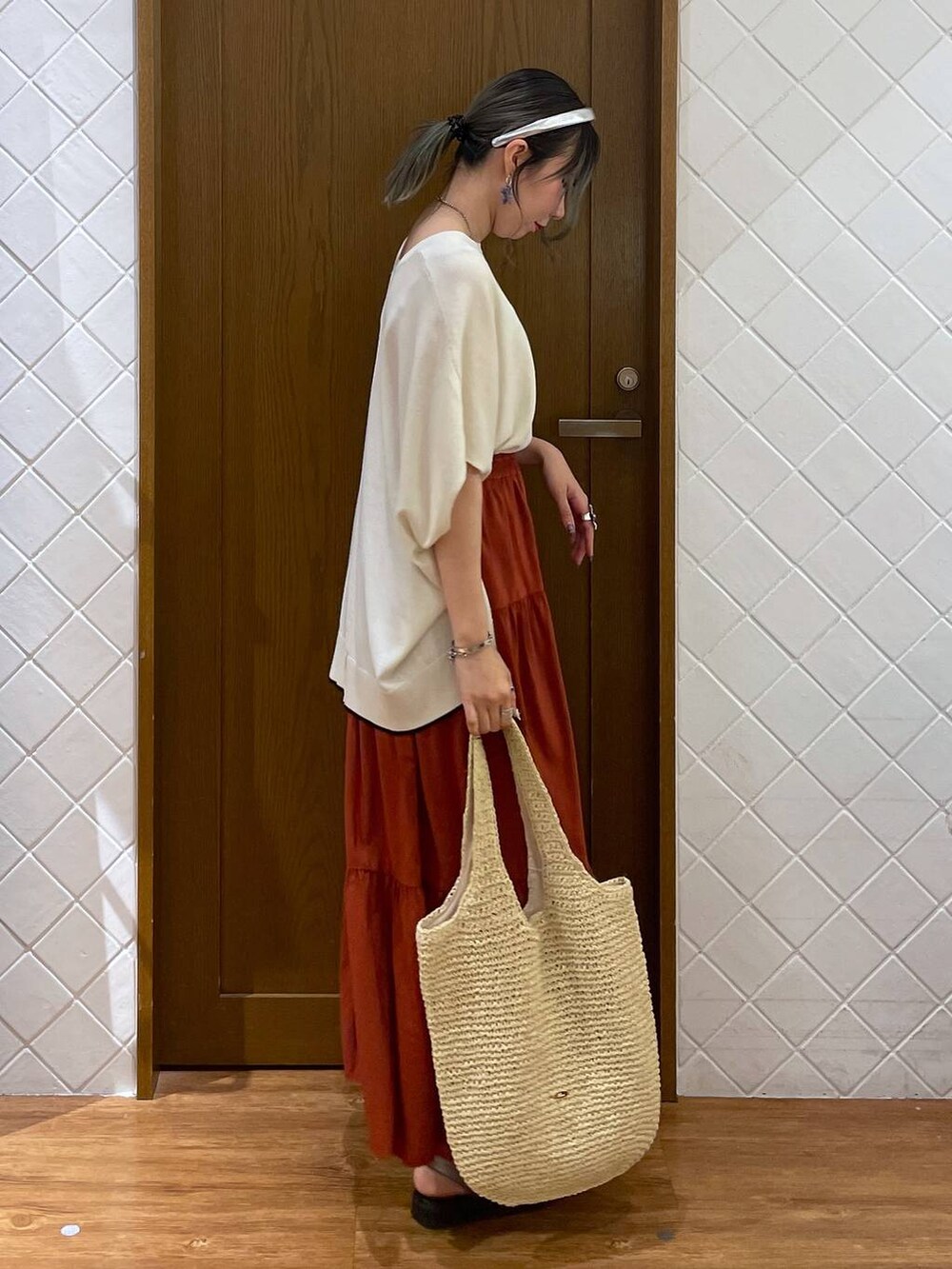ベージュ系のショルダーバッグ、ホワイト系のニット/セーター、ブラウン系のサンダルを着用したレディースの夏コーディネートの2枚目の写真