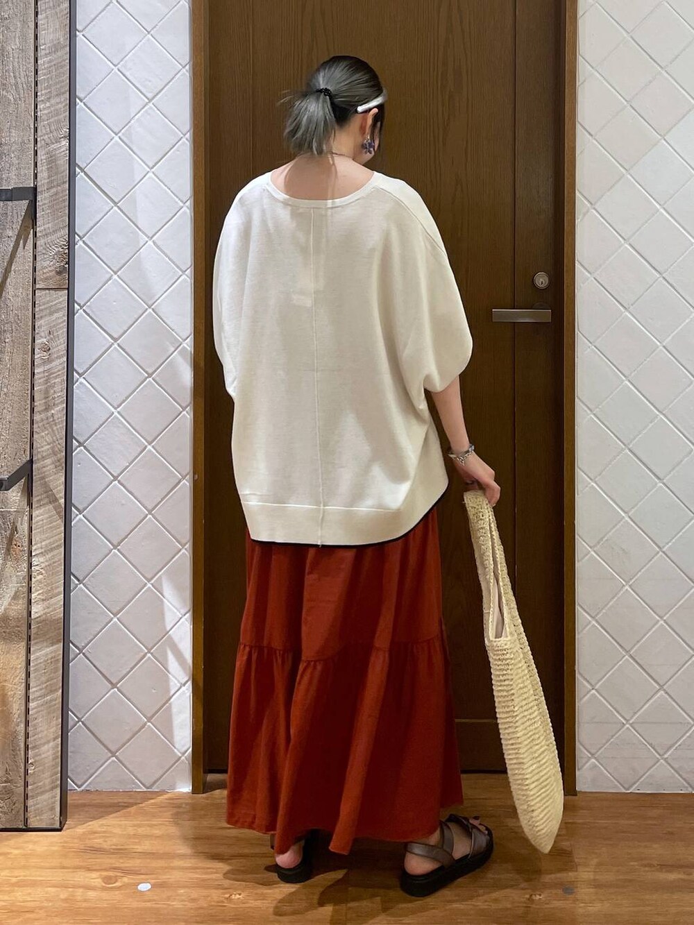 ベージュ系のショルダーバッグ、ホワイト系のニット/セーター、ブラウン系のサンダルを着用したレディースの夏コーディネートの4枚目の写真