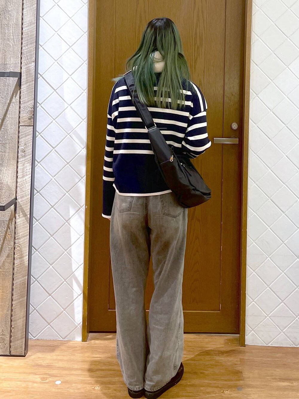 ブラック系のショルダーバッグ、グレー系のデニムパンツ、ブラック系のローファーを着用したレディースの冬コーディネートの4枚目の写真