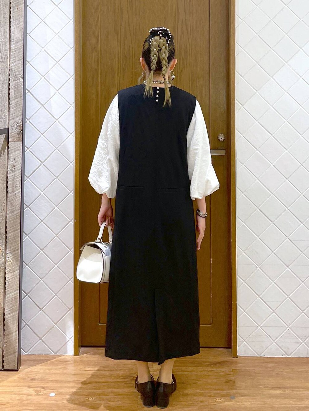 ホワイト系のシャツ/ブラウス、ブラック系のパンプス、ブラック系のジャンパースカートを着用したレディースの冬コーディネートの4枚目の写真