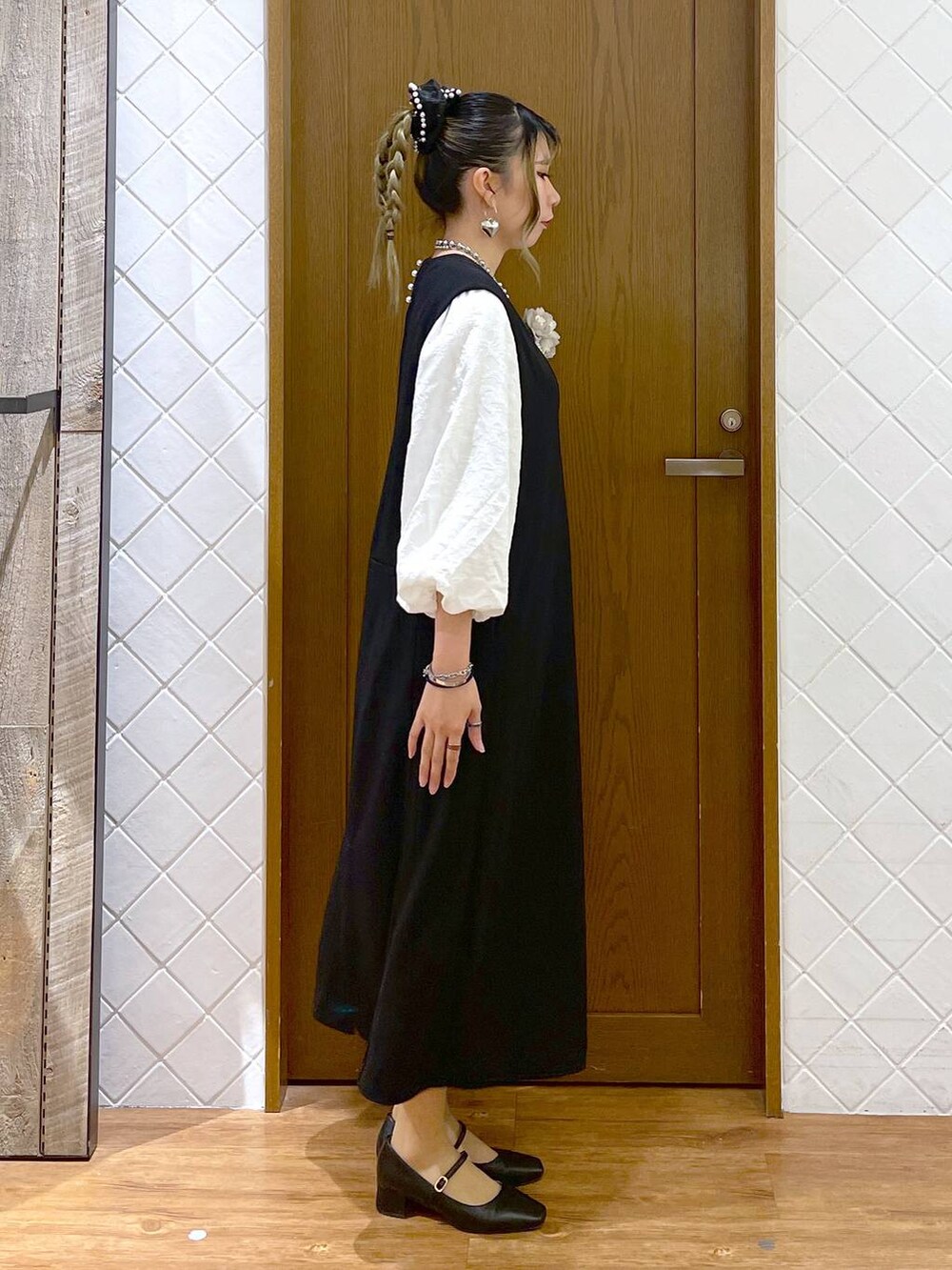 ホワイト系のシャツ/ブラウス、ブラック系のパンプス、ブラック系のジャンパースカートを着用したレディースの冬コーディネートの3枚目の写真