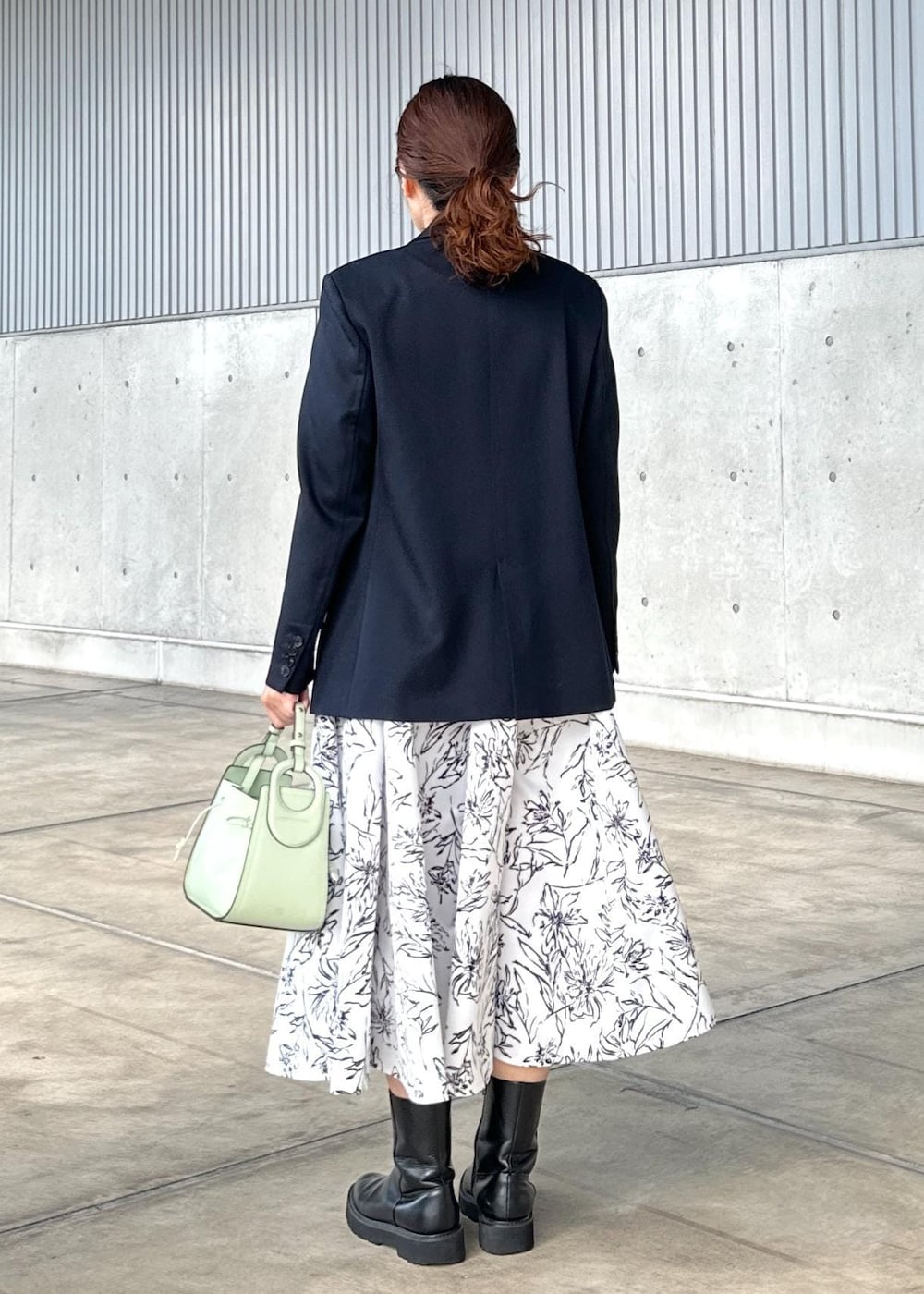 グリーン系のハンドバッグ、ホワイト系のスカート、ゴールド系のTシャツ/カットソーを着用したレディースの冬コーディネートの3枚目の写真