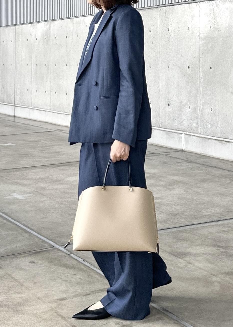 ベージュ系のトートバッグ、ブルー系のテーラードジャケット、ブルー系のその他パンツを着用したレディースの夏コーディネートの2枚目の写真