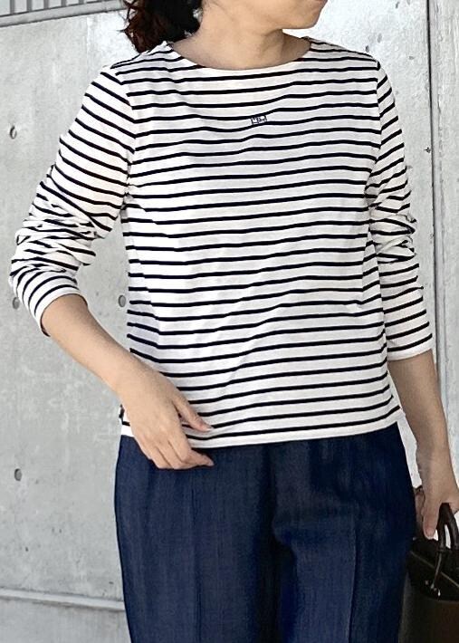 グリーン系のトートバッグ、ブルー系のその他パンツ、ホワイト系のTシャツ/カットソーを着用したレディースの秋コーディネートの5枚目の写真