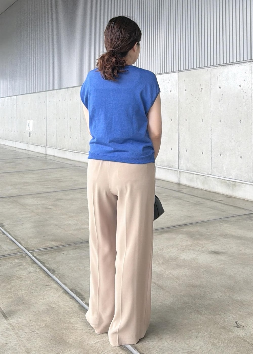 ベージュ系のその他パンツ、ブラック系のハンドバッグ、ブルー系のニット/セーターを着用したレディースの夏コーディネートの3枚目の写真