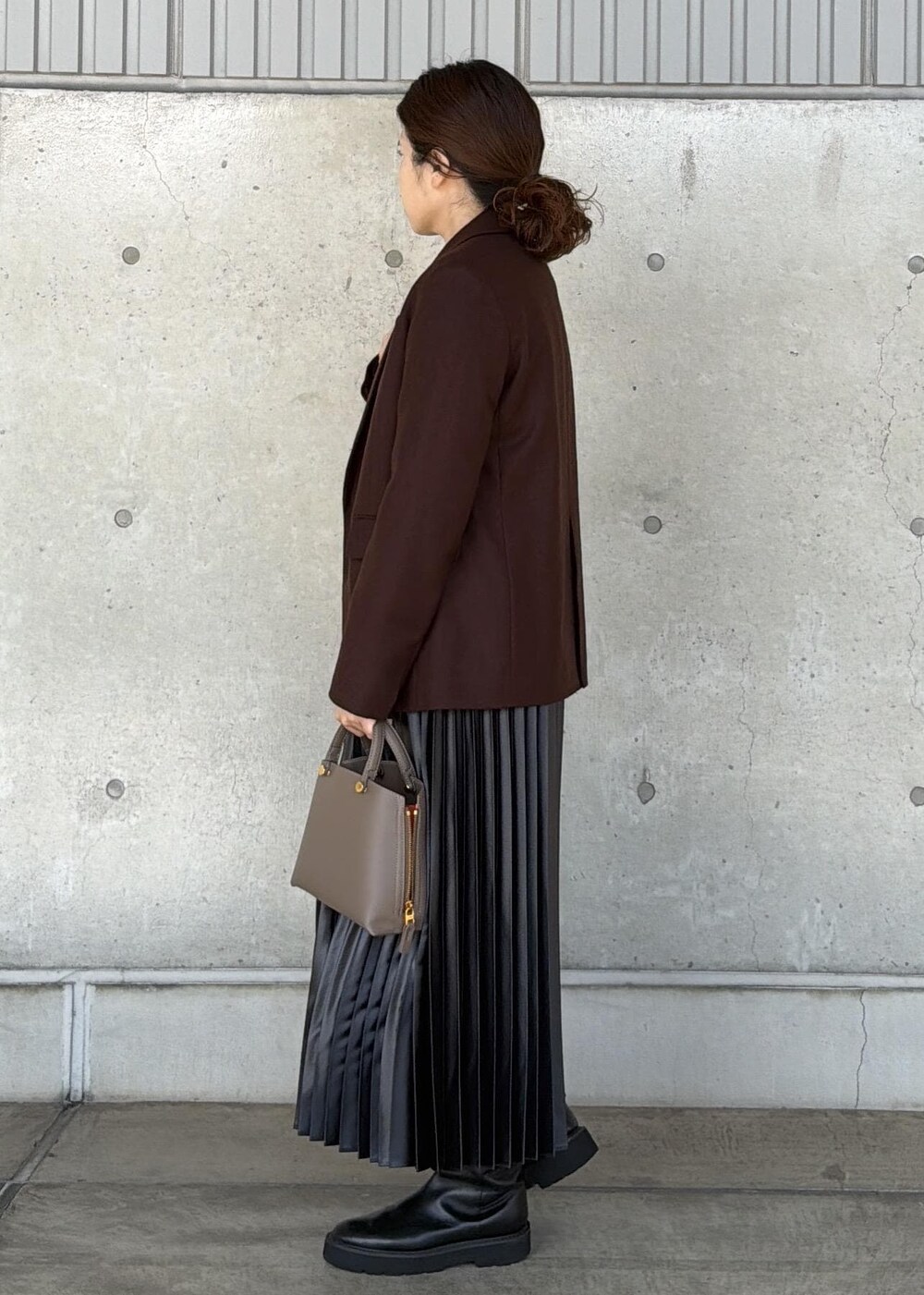 ブラウン系のハンドバッグ、ブラック系のカーディガン/ボレロ、ブラック系のスカートを着用したレディースの秋コーディネートの2枚目の写真