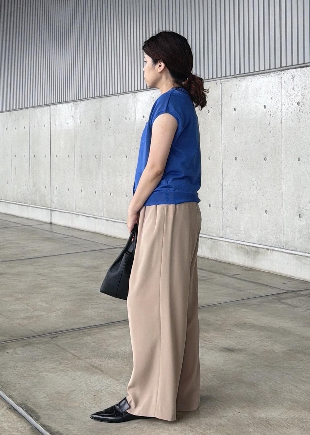 ベージュ系のその他パンツ、ブラック系のハンドバッグ、ブルー系のニット/セーターを着用したレディースの夏コーディネートの2枚目の写真