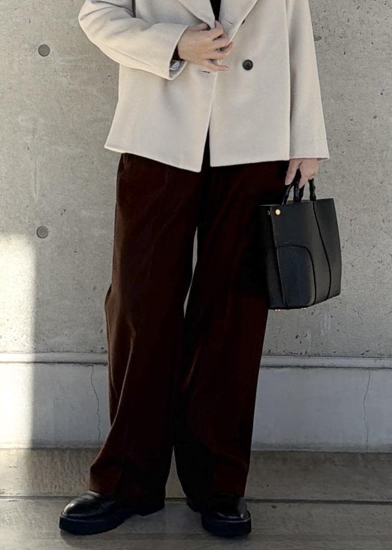 ブラック系のハンドバッグ、ホワイト系のステンカラーコート、ブラウン系のニット/セーターを着用したレディースの冬コーディネートの6枚目の写真