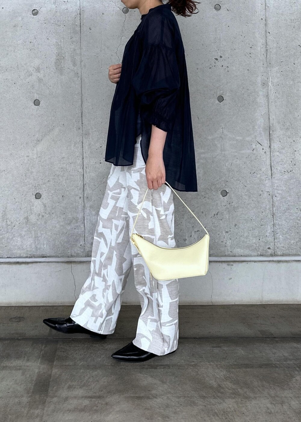 ベージュ系のハンドバッグ、ブラック系のパンプス、ブルー系のシャツ/ブラウスを着用したレディースの春コーディネートの2枚目の写真