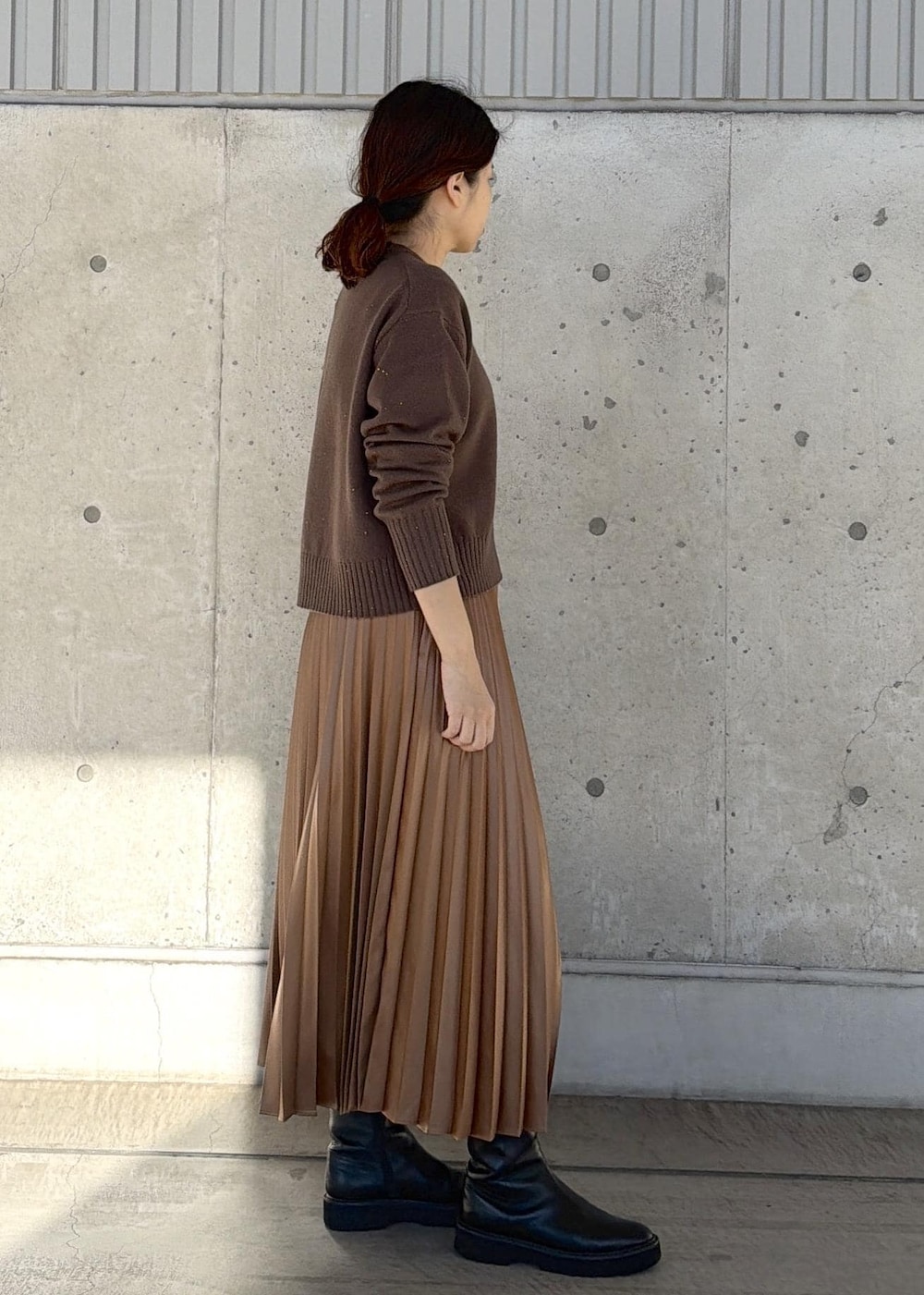 ブラック系のハンドバッグ、イエロー系のスカート、ブラウン系のニット/セーターを着用したレディースの冬コーディネートの2枚目の写真