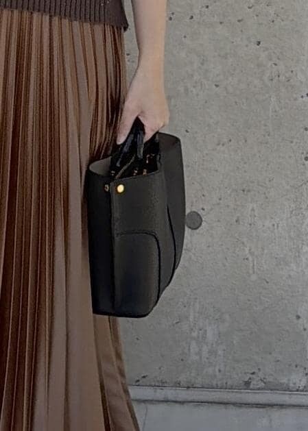 ブラック系のハンドバッグ、イエロー系のスカート、ブラウン系のニット/セーターを着用したレディースの冬コーディネートの6枚目の写真