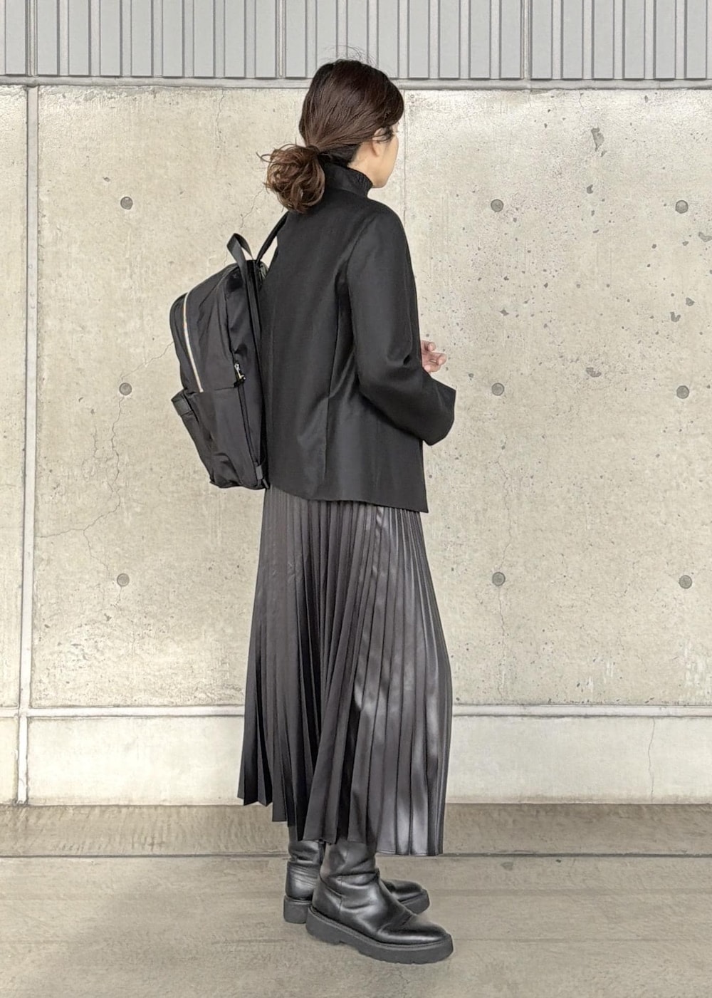 ブラック系のバックパック/リュック、ブラック系のスカート、ブラック系のニット/セーターを着用したレディースの冬コーディネートの2枚目の写真