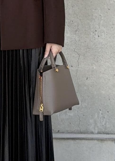 ブラウン系のハンドバッグ、ブラック系のカーディガン/ボレロ、ブラック系のスカートを着用したレディースの秋コーディネートの6枚目の写真