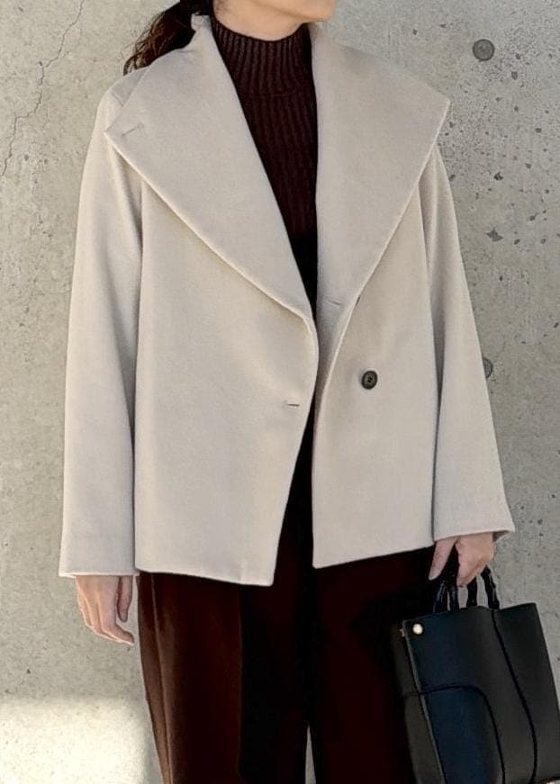 ブラック系のハンドバッグ、ホワイト系のステンカラーコート、ブラウン系のニット/セーターを着用したレディースの冬コーディネートの4枚目の写真