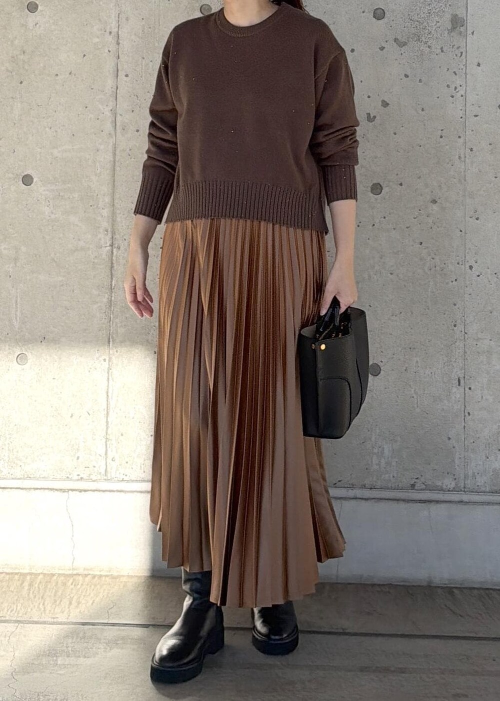 ブラック系のハンドバッグ、イエロー系のスカート、ブラウン系のニット/セーターを着用したレディースの冬コーディネートの7枚目の写真