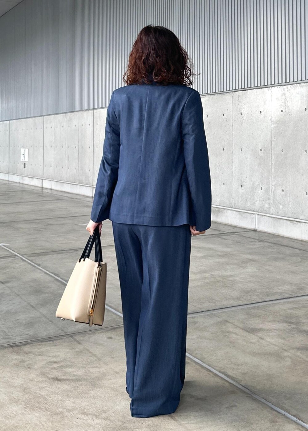 ベージュ系のトートバッグ、ブルー系のテーラードジャケット、ブルー系のその他パンツを着用したレディースの夏コーディネートの3枚目の写真
