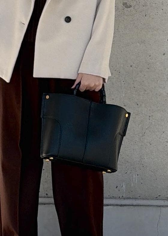 ブラック系のハンドバッグ、ホワイト系のステンカラーコート、ブラウン系のニット/セーターを着用したレディースの冬コーディネートの7枚目の写真