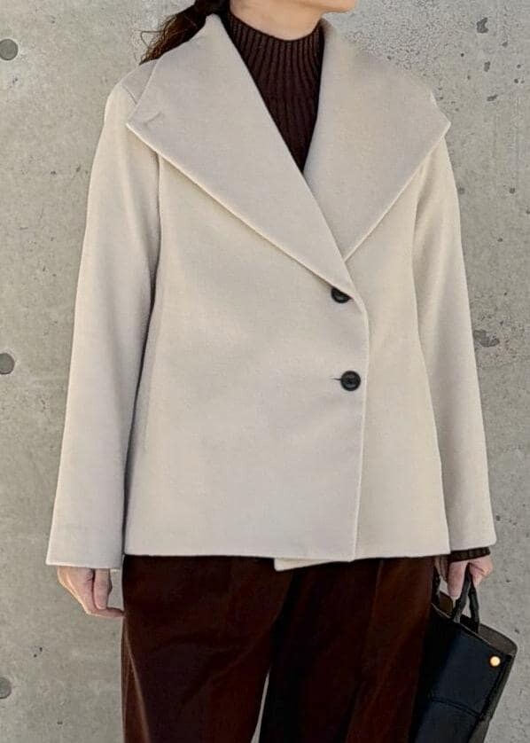 ブラック系のハンドバッグ、ホワイト系のステンカラーコート、ブラウン系のニット/セーターを着用したレディースの冬コーディネートの5枚目の写真