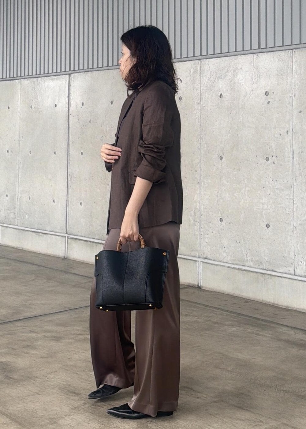 ブラック系のハンドバッグ、ブラウン系のノーカラージャケット、ブラウン系のTシャツ/カットソーを着用したレディースの春コーディネートの2枚目の写真