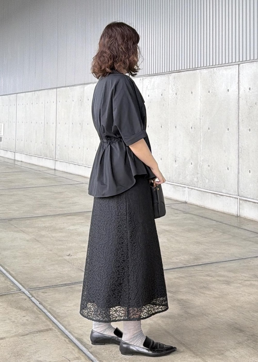 ブラック系のハンドバッグ、ブラック系のシャツ/ブラウス、ブラック系のスカートを着用したレディースの春コーディネートの2枚目の写真