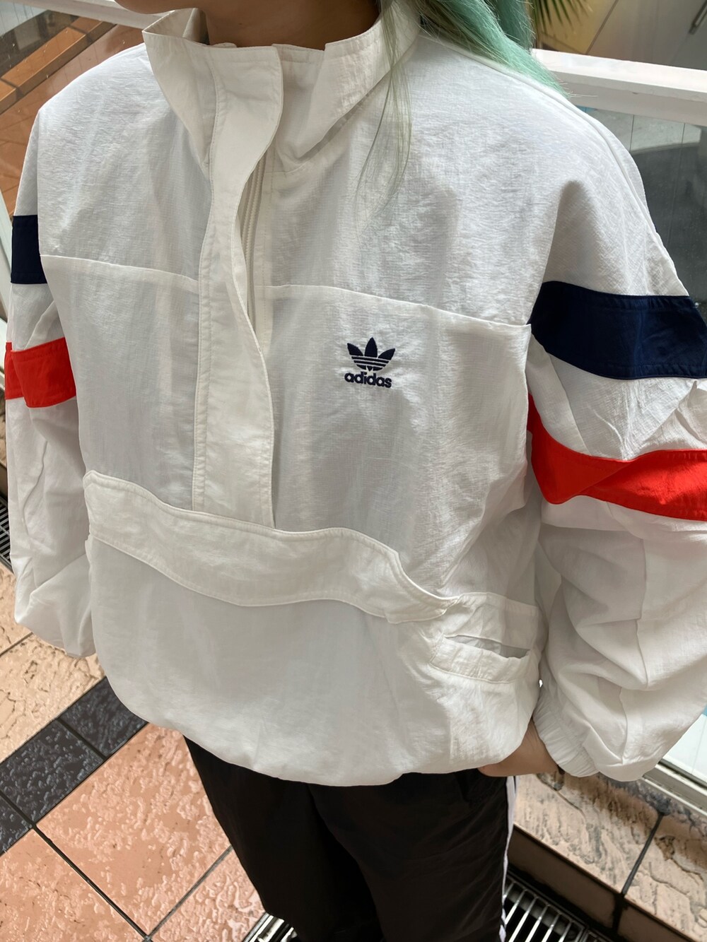 ホワイト系のナイロンジャケット、ブラック系のパンツ、ブラック系のスニーカーを着用したレディースの春コーディネートの4枚目の写真