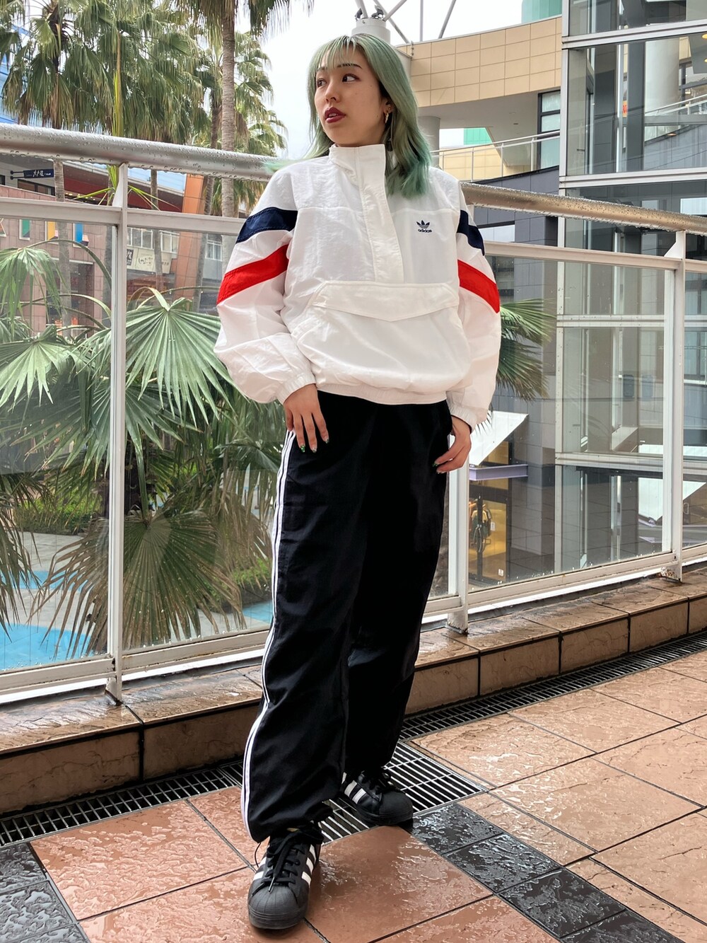 ホワイト系のナイロンジャケット、ブラック系のパンツ、ブラック系のスニーカーを着用したレディースの春コーディネートの2枚目の写真