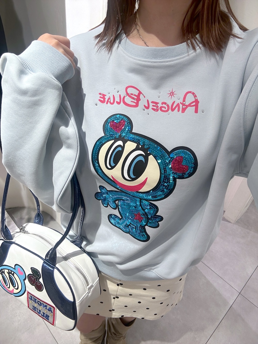 ブルー系のTシャツ/カットソー、ブルー系のボストンバッグ、ホワイト系のスカートを着用したレディースの春コーディネートの4枚目の写真