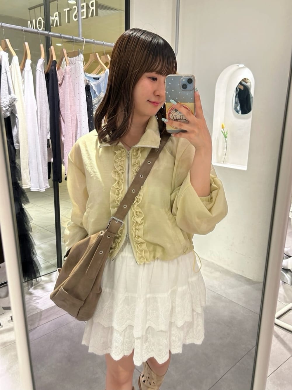 イエロー系のブルゾン、ブラウン系のトートバッグ、ホワイト系のその他パンツを着用したレディースの夏コーディネートの3枚目の写真