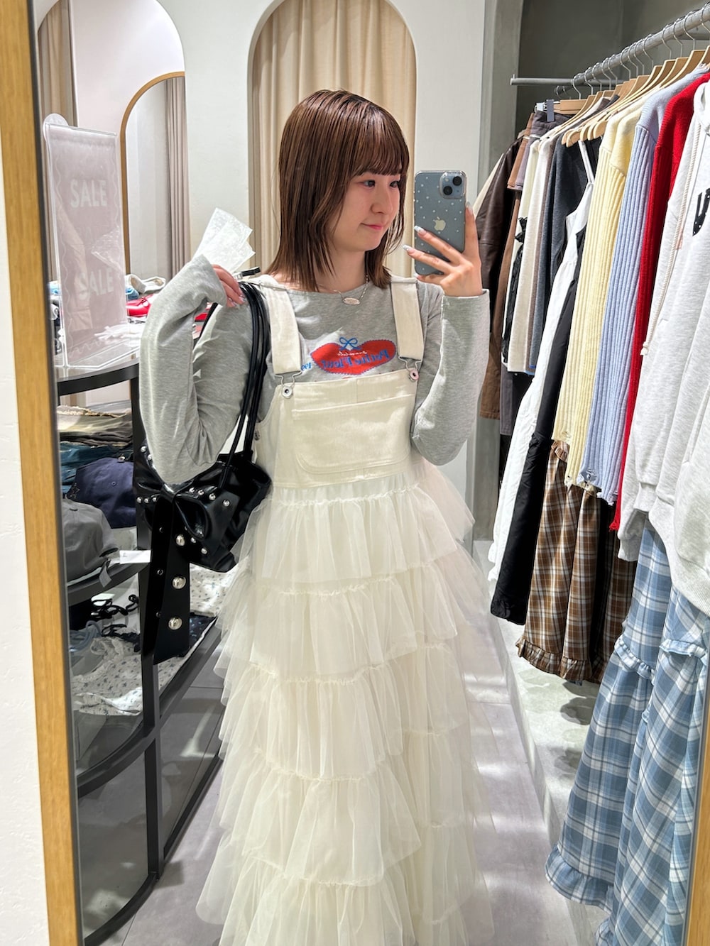 グレー系のTシャツ/カットソー、ホワイト系のジャンパースカート、ブラック系のトートバッグを着用したレディースの春コーディネートの2枚目の写真