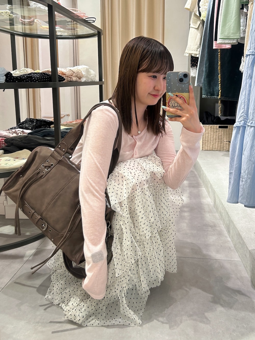 ピンク系のTシャツ/カットソー、ブラウン系のボストンバッグ、ホワイト系のスカートを着用したレディースの夏コーディネートの2枚目の写真