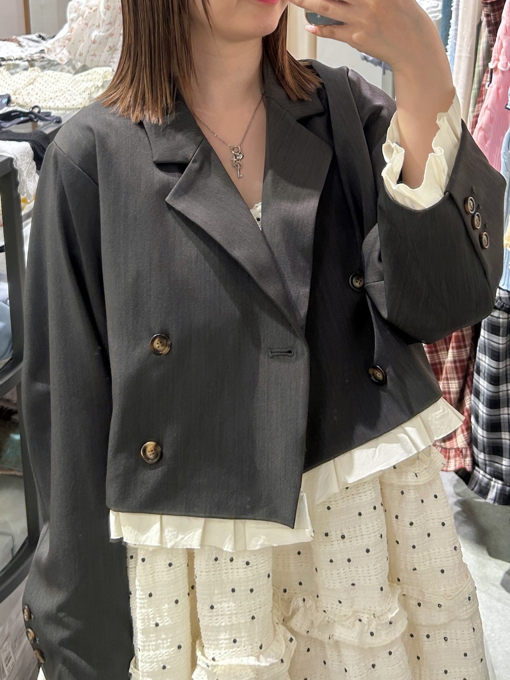 グレー系のテーラードジャケット、ブラック系のトートバッグ、ホワイト系のワンピースを着用したレディースの春コーディネートの5枚目の写真