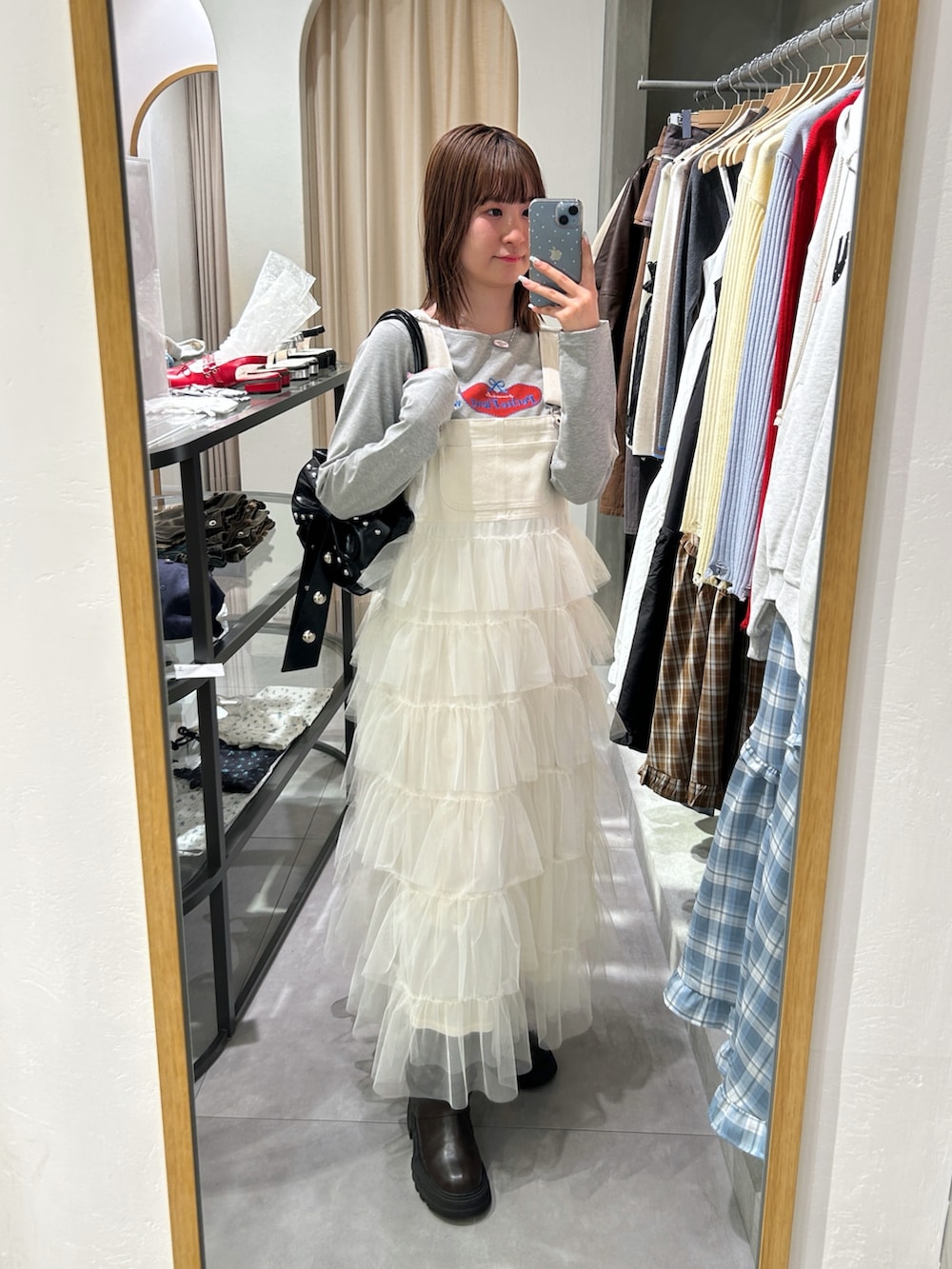 グレー系のTシャツ/カットソー、ホワイト系のジャンパースカート、ブラック系のトートバッグを着用したレディースの春コーディネートの4枚目の写真