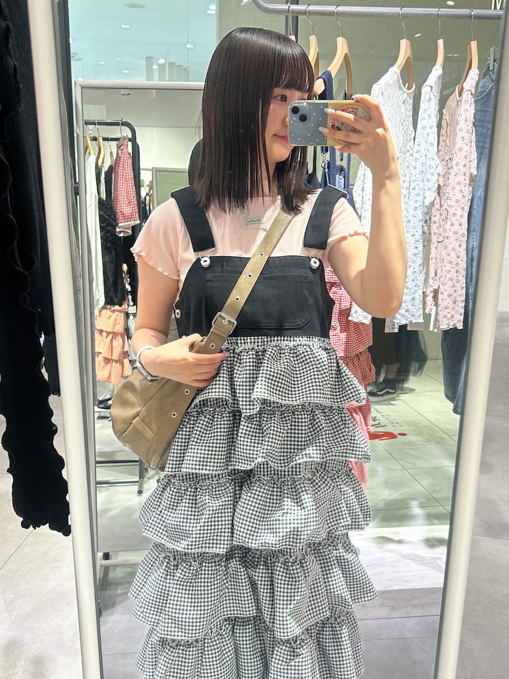 ピンク系のTシャツ/カットソー、ブラウン系のトートバッグ、ブラック系のジャンパースカートを着用したレディースの春コーディネートの5枚目の写真
