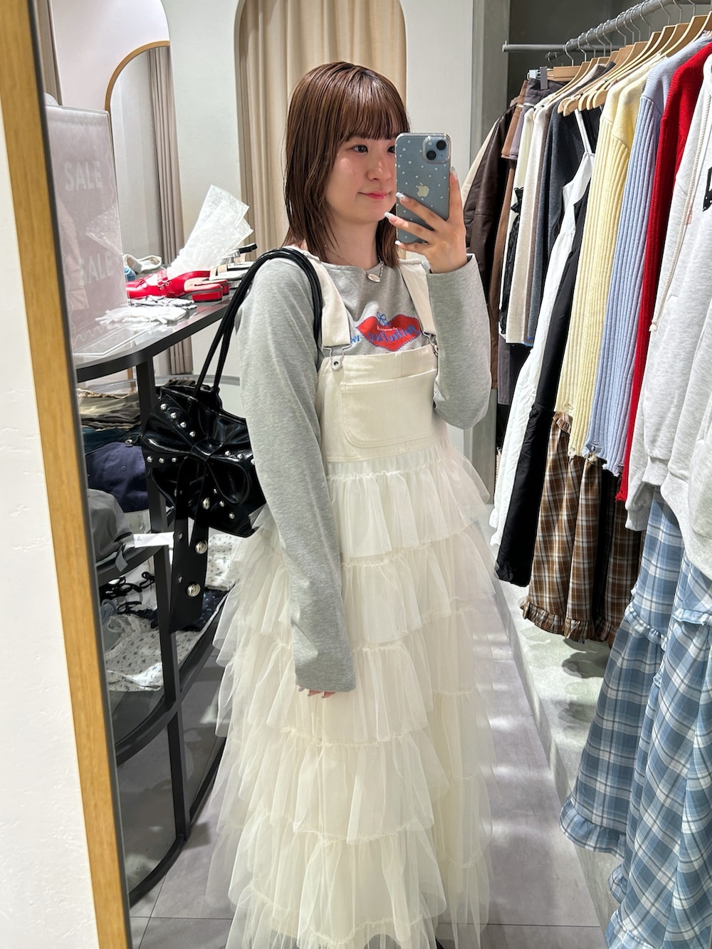 グレー系のTシャツ/カットソー、ホワイト系のジャンパースカート、ブラック系のトートバッグを着用したレディースの春コーディネートの3枚目の写真