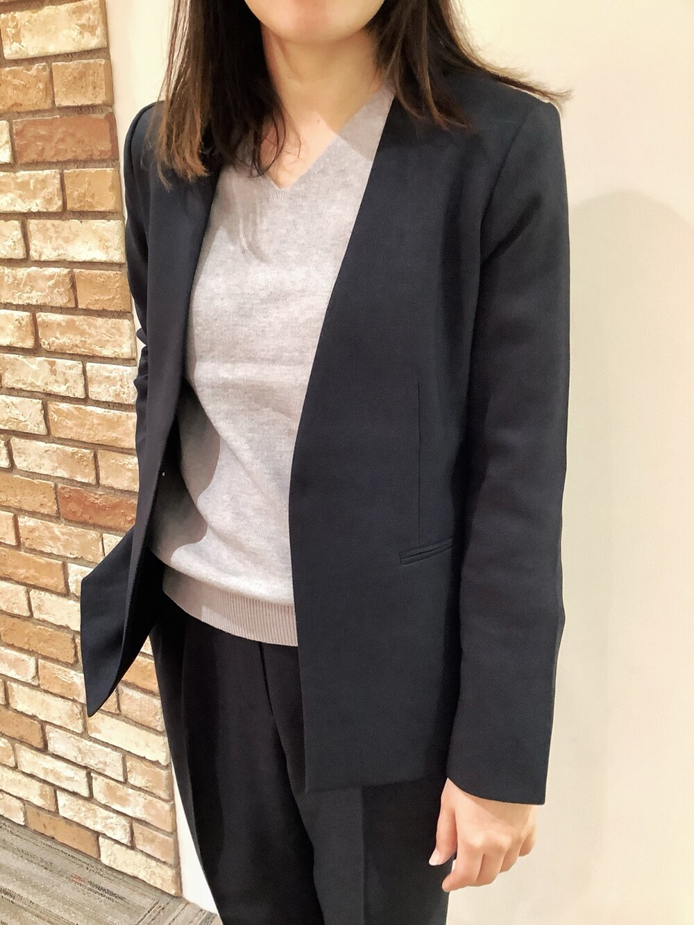 ブルー系のスラックス、ブルー系のノーカラージャケット、グレー系のニット/セーターを着用したレディースの秋コーディネートの2枚目の写真