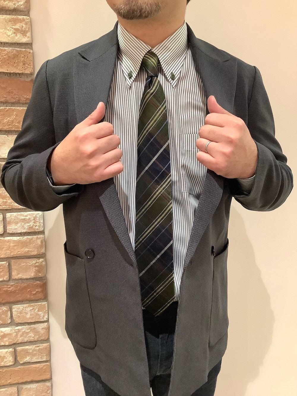 グリーン系のビジネスシャツ、ブラウン系のネクタイを着用したメンズの冬コーディネートの3枚目の写真