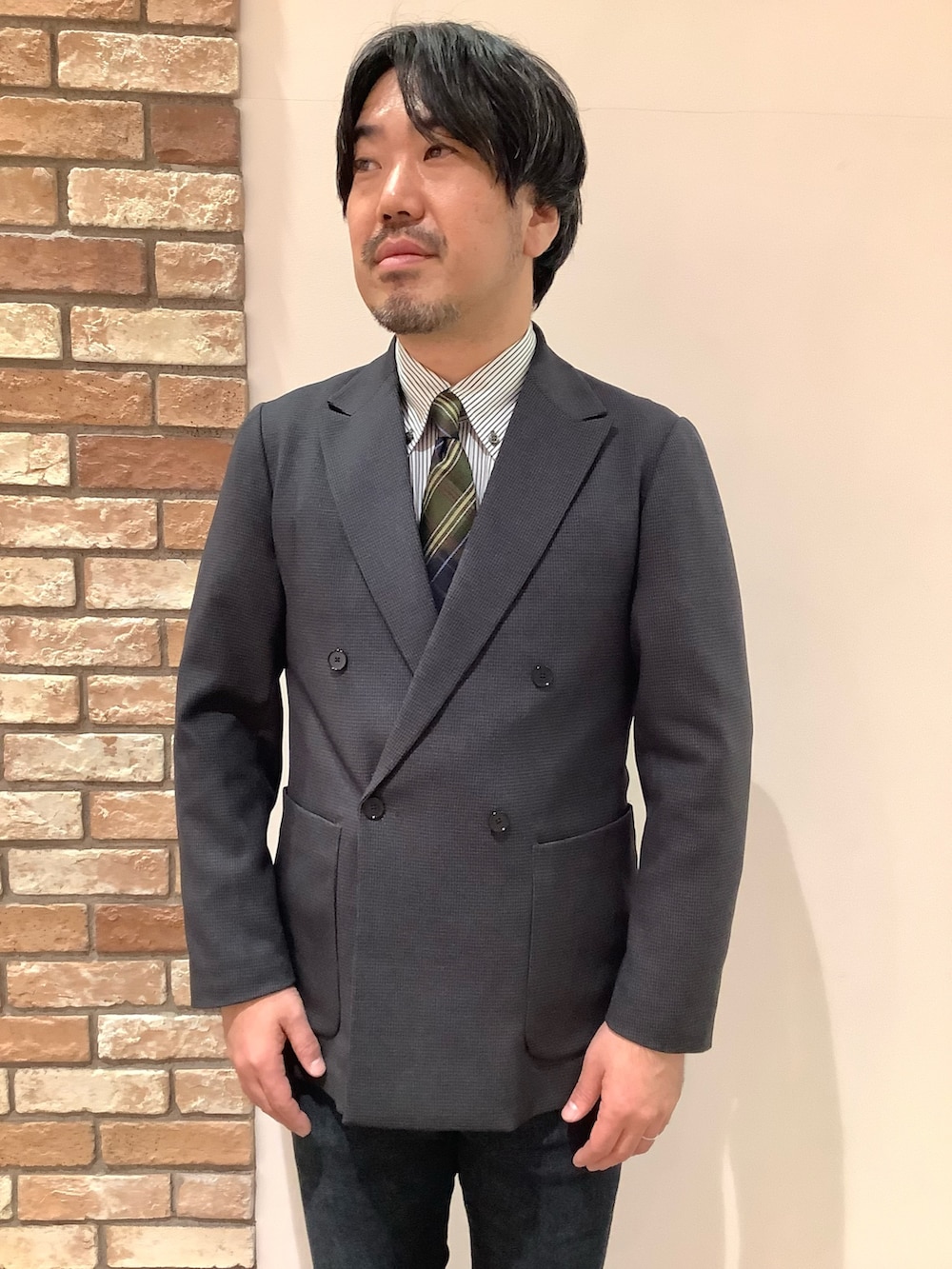 グリーン系のビジネスシャツ、ブラウン系のネクタイを着用したメンズの冬コーディネートの2枚目の写真