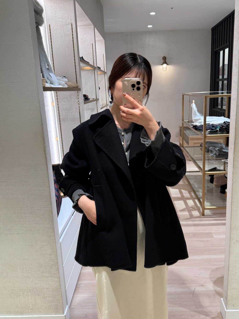 グレー系のカーディガン/ボレロ、ホワイト系のスカート、ブラック系のショルダーバッグを着用したレディースの秋コーディネートの5枚目の写真