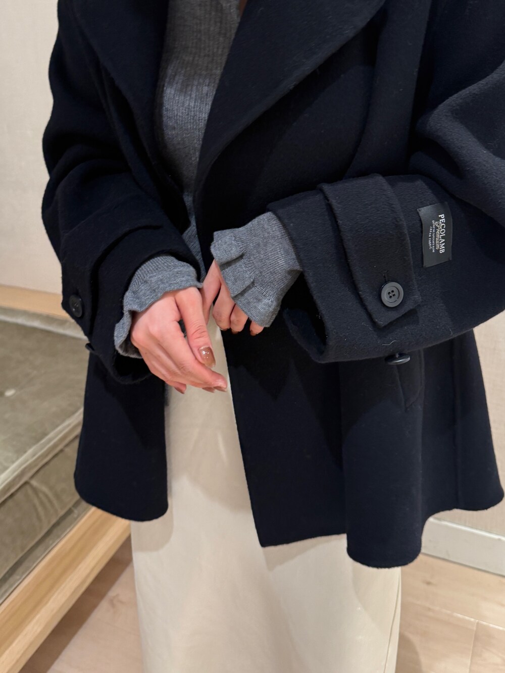 グレー系のカーディガン/ボレロ、ホワイト系のスカート、ブラック系のショルダーバッグを着用したレディースの秋コーディネートの6枚目の写真