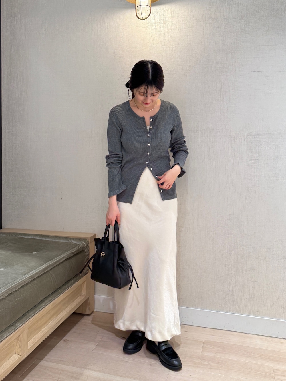 グレー系のカーディガン/ボレロ、ホワイト系のスカート、ブラック系のショルダーバッグを着用したレディースの秋コーディネートの2枚目の写真