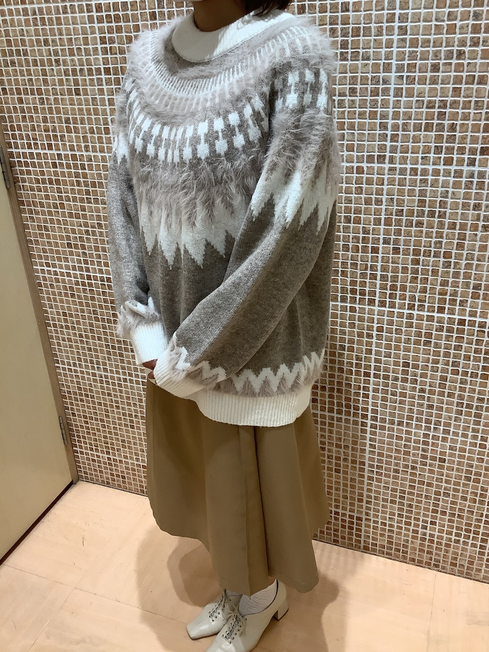 ブラウン系のニット/セーターを着用したレディースの秋コーディネートの2枚目の写真