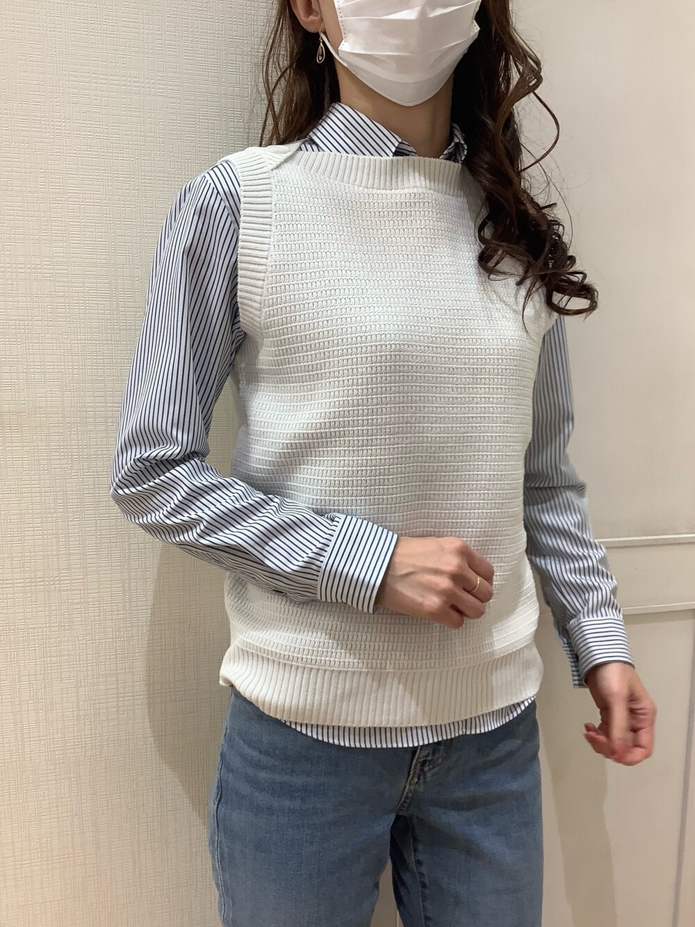 ホワイト系のベスト、ブルー系のビジネスシャツを着用したレディースの春コーディネートの3枚目の写真