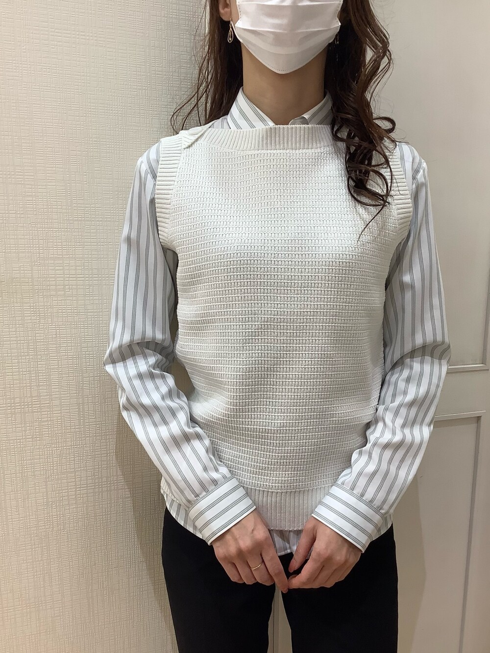 ホワイト系のベスト、グリーン系のビジネスシャツを着用したレディースの春コーディネートの4枚目の写真